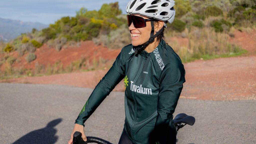 A woman cyclist enjoying a ride on a sunny day, wearing sports gear and helmet.
